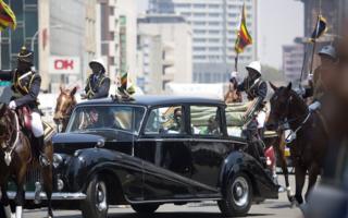 በሌላ በኩል ደግሞ የዚምባብዌው ፕሬዝዳንት ሮበርት ሙጋቤና ባለቤቱ ግሬስ ሙጋቤ በሃራሬ የፓርላማ መክፈቻ ላይ ለመገኘት በሮልስሮይስ መኪና ይታያሉ።