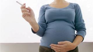 A pregnant woman holding a cigarette