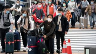 Китайские путешественники в масках в аэропорту