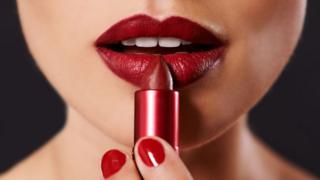 Mujer colocando labial en sus labios