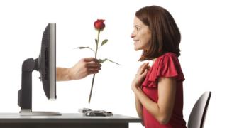 mujer recibiendo una rosa que sale de su computadora