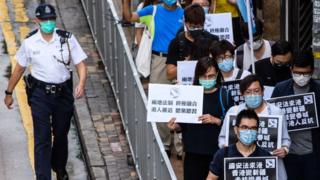 Pro-democracy protesters hold black placards as they march on the Chinese Liaison Office in Hong Kong