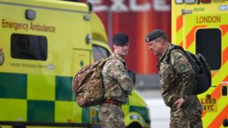 Военнослужащие британских вооруженных сил стоят у лондонских машин скорой помощи на автостоянке лондонского выставочного центра ExCeL