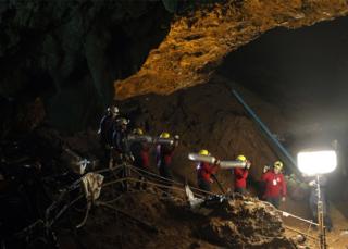 Thai officials carry oxygen tanks through a cave complex during a rescue operation for a missing football team at the Tham Luang cave in Tham Luang Khun Nam Nang Noon Forest Park in Chiang Rai province, Thailand, 30 June 2018