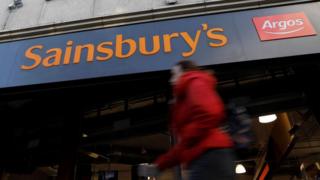 Woman walks past a Sainsbury's store with an Argos outlet inside