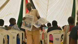 A newspaper vendor hawks copies of the daily edition with a headline photo of visiting US President Barack Obama with his host Kenyan President Uhuru Kenyatta, on July 26, 2015 in the village of Kogelo in Siaya county, where residents had gathered to watch a televised live broadcast of Obama's speech
