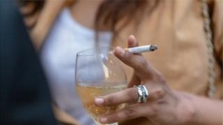 Келих вина і цигарка в руках у жінки