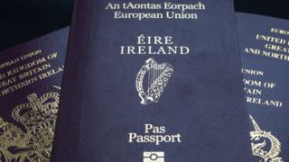 An Irish passport is seen on top of a pile of UK passports