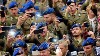 Soldiers hold their camera phones up and take pictures