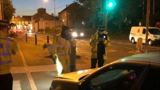 Police standing in front of a car that has been pulled over
