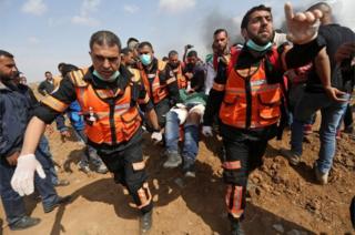 Warga Palestina membawa seorang pria yang terluka selama bentrokan dengan pasukan keamanan Israel.