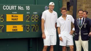 Isner and Mahut pose with the scoreboard after their marathon match at Wimbledon