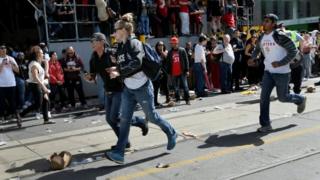 Police and spectators gather in scattered crowds after gunfire has been fired in the area where thousands of people gathered in Nathan Phillips Square.