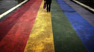 Man stands on rainbow flag pavement ahead of Gay pride Sydney in 2013