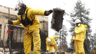 Поисково-спасательные бригады копают сгоревшие останки бизнеса, когда они ищут человеческие останки в Раю, штат Калифорния.