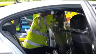 An AA engineer installing a perspex screen in a taxi