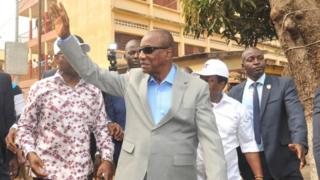 Guinea President Alpha Conde of Guinea dey wave after im cast vote on February 4, 2018 outside one polling station for Conakry