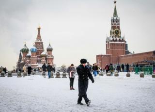 Военнослужащий идет перед собором Василия Блаженного и Кремлем