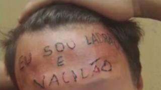 Tattoo on the boy's forehead reads "I'm a thief and loser"