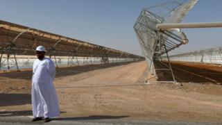 A man stands in front of rows of parabolic shaped mirrors at the Shams 1, Concentrated Solar Power plant, in al-Gharibiyah district on the outskirts of Abu Dhabi (17 March 2013)