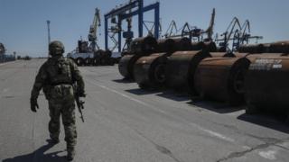 Un militar ruso camina por el territorio del puerto marítimo de carga en Mariupol
