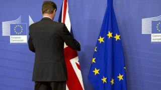 A man adjusts a UK flag ahead of press conference in Brussels