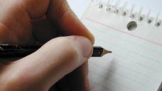 Mão esrevendo em caderno