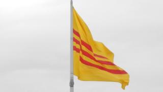 Zoom-in of a photo of the flags of the United States and the former South Vietnam flying outside the Eden Center shopping complex in the Washington suburb of Falls Church on 28 October 2012.