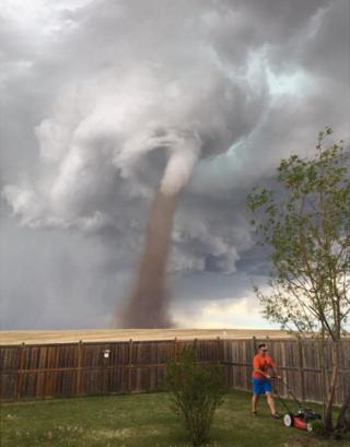 La foto de Theunis Wessels podando el césped con el tornado tras él