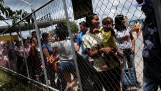 Венесуэльцы стоят в очереди, чтобы показать свои паспорта или удостоверения личности на пограничном пункте Пакарайма в Бразилии в августе 2018 года