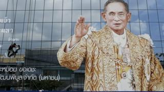 Тайские работники устанавливают памятное траурное сообщение рядом с портретом покойного тайского короля Пумипона Адульядета в здании компании в Бангкоке, Таиланд, 24 октября 2016 года.