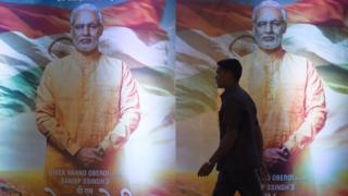 An Indian man walks in front of posters of the upcoming Bollywood film 'PM Narendra Modi' - a biopic on Indian Prime Minister Narendra Modi, during an event to launch the poster of the film in Mumbai on January 7, 2019. -