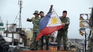 Philippine soldiers aboard their armoured personnel carrier celebrate after President Rodrigo Duterte declared Marawi City "liberated", inside the battle area of Bangolo in Marawi on October 17, 2017.