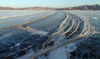 A car drives along a road connecting the banks of the ice-covered Yenisei River