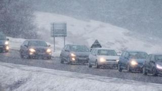 Snow falls on cars