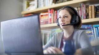 Stock image of woman with headset working at home