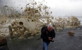 A man runs from sea spray as storms hit Cape Town, South Africa, June 7, 2017.