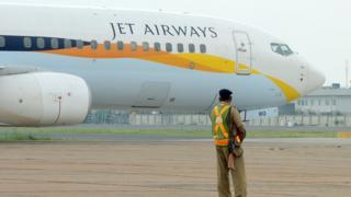 Индийский сотрудник службы безопасности выглядит как самолет такси Jet Airways после приземления в международном аэропорту имени Индиры Ганди в Нью-Дели 12 сентября 2012 года