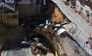 A huge sinkhole swallows six cars.
