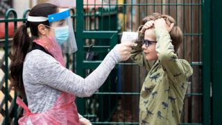 A member of staff takes a child's temperature at a school in London - 4 June 2020