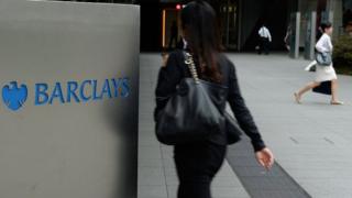 People walking by a Barclays sign