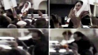 Sawirro la isku keenay oo laga soo jaray muuqaal uu baahiyay taleefishinka Dawn ee Pakistan, waxa uu muujinayaa Bhutto oo gacanta u haadinaysa taageerayaasheeda, iyo nin bastoolad ridaya magaalada CRawalpindi 27 December 2007.