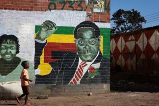 A boy pbades a mural of former Zimbabwean President Robert Mugabe on July 29, 2018 in Harare, Zimbabwe.