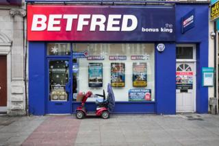 An electric buggy stands outside a betting shop on a high street