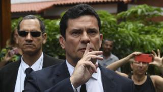 Juiz Sergio Moro faz sinal de silêncio, com o dedo indicador erguido em frente à boca, ao chegar à residência de Bolsonaro, no Rio