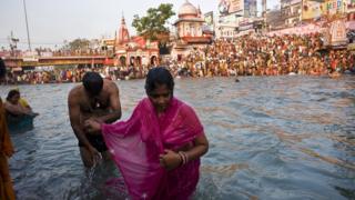 A Hindu couple holds hands after bathing in the river Ganges as devotees crowd both banks during the Kumbh Mela festival in Haridwar on 13 April 2010