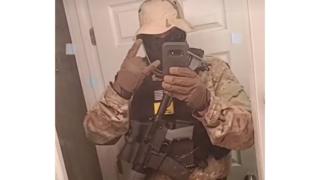 Screengrab showing a man with an assault rifle making a TikTok video