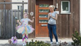 Mother and daughter clapping outside their house