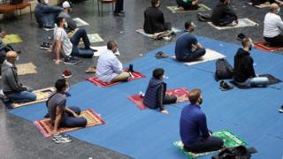Worshippers sit on their prayer mats during Friday prayers at a church in Berlin