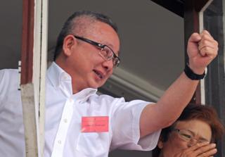 นายสนธิ ลิ้มทองกุล อดีตแกนนำกลุ่มพันธมิตรประชาชนเพื่อประชาธิปไตย ชูมือให้กับผู้สนับสนุนซึ่งเดินทางมาให้กำลังใจครั้งเข้ารับทราบข้อกล่าวหาในคดีปิดสนามบิน ที่กองปราบปราม เมื่อปี 2553